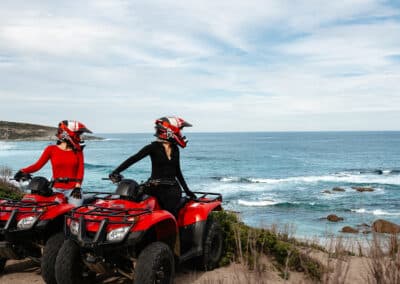 Two riders on red quad bikes pause at Cape Kersaint during the Edge of the Earth Quad Tour with Kangaroo Island Outdoor Action, overlooking the rugged Southern Ocean coastline on Kangaroo Island.