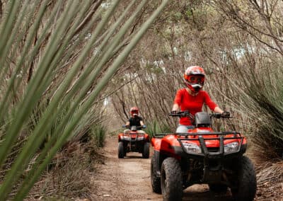 Guests riding quad bikes through narrow yacca-lined bush tracks on Kangaroo Island